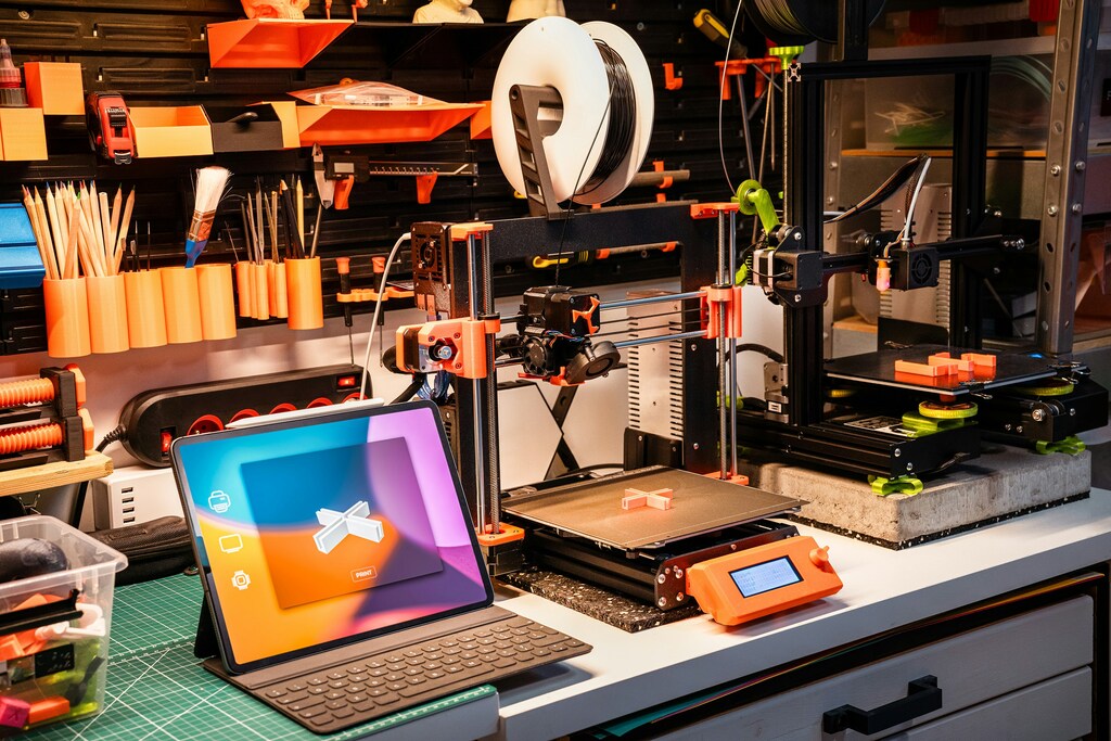 Un escritorio ordenado con una impresora 3D, carretes de filamento y herramientas, ilustrando el checklist de lo que necesitas para tu primera impresión 3D.